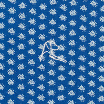 RHOBACK’s The Agave 2.0 Performance Polo in Short Stop Blue/Seafoam features a repeating white leaf pattern, an embroidered dog head, and UPF sun-protection with moisture-wicking fabric for comfort and style.