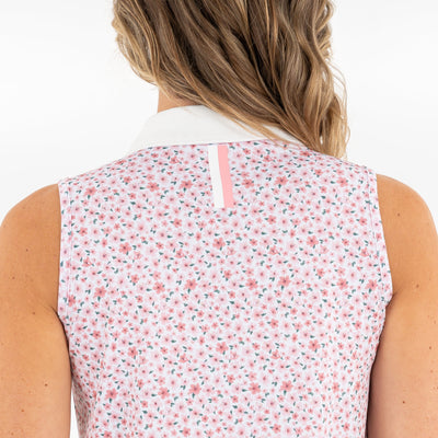 A person with wavy, light brown hair is shown from the back wearing the RHOBACK Brooke Sleeveless Performance Polo | The Azalea 2.0 in White/Pearl Pink, featuring a white collar, a pink and white floral pattern, and moisture-wicking fabric.