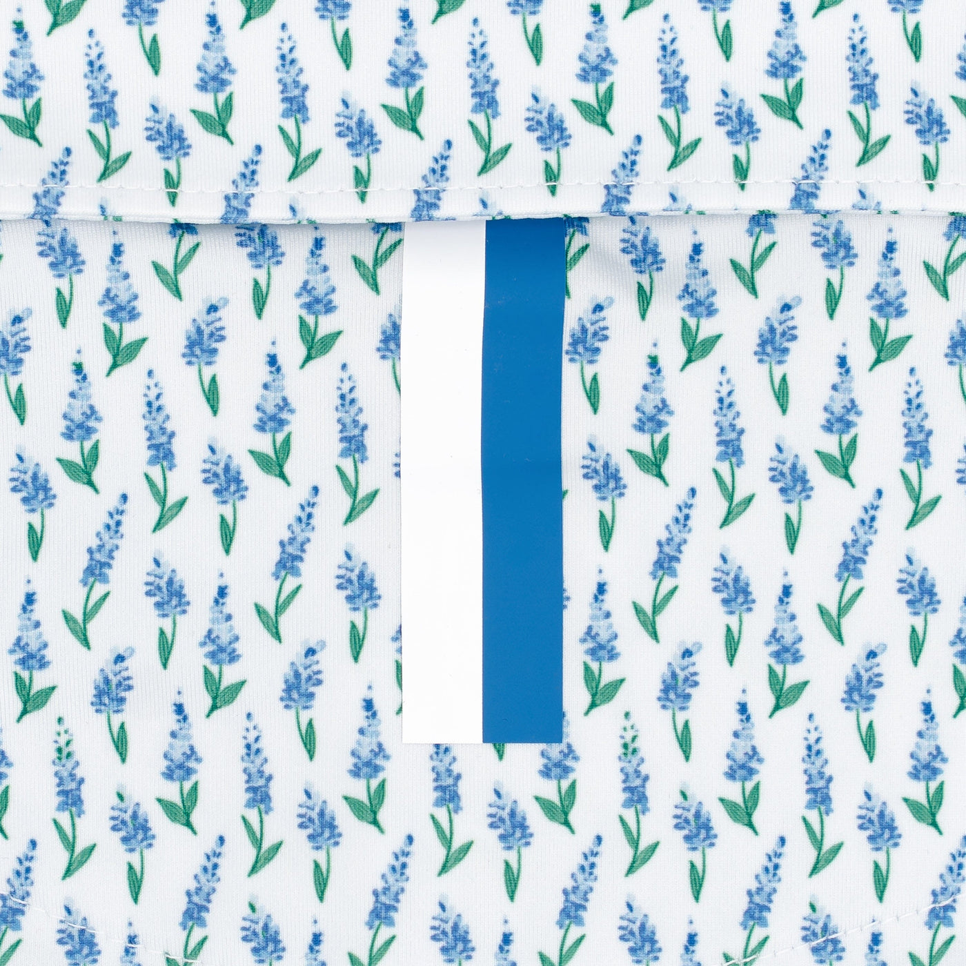 A close-up of RHOBACK's The Blue Bonnet 2.0 Performance Polo in White/Lake Blue, featuring moisture-wicking fabric with small blue flowers, green stems, and a central white strip with a vertical blue stripe for added style.