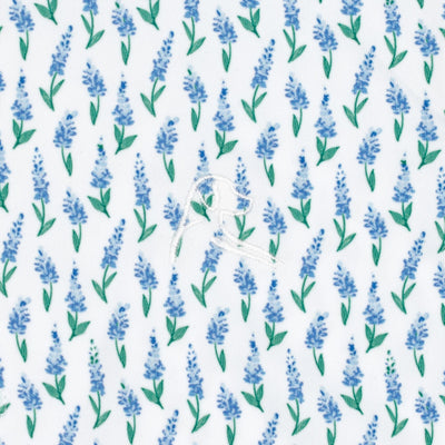 The Lil' Blue Bonnet 2.0 Performance Polo by RHOBACK features a playful white fabric with blue lavender sprigs, green leaves, and a stitched dog outline—delivering sun protection and charm for toddlers.