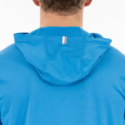 A person is shown from the back wearing the RHOBACK Blitz Tech Hoodie in Birdie Blue/Sapphire Blue, made with SilverKnit fabric. The hood is up and a small reflective strip appears on the back of the hood.