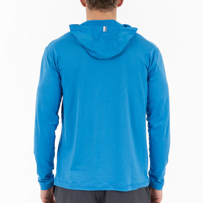 A person is shown from the back wearing an RHOBACK Blitz Tech Hoodie | Heather - Birdie Blue/Sapphire Blue with the hood up (not covering the head) and dark shorts, set against a plain white background.
