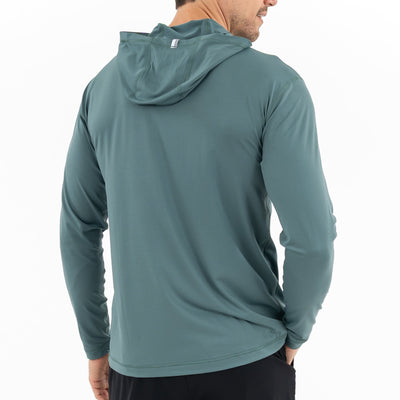 A man is shown from the back wearing a RHOBACK Blitz Tech Hoodie in Heather - Jungle Green/Dusty Pine and black pants against a plain white background.