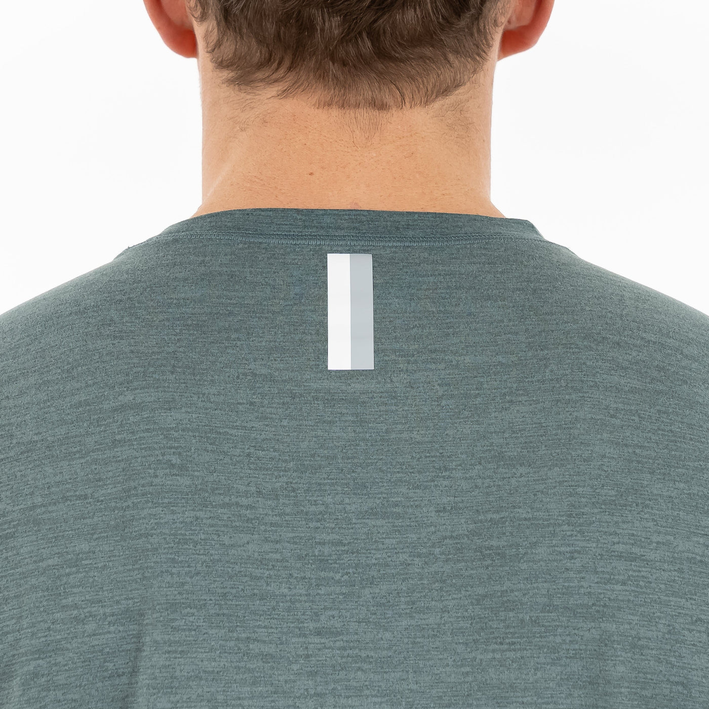 The back view shows a person in the RHOBACK Tailwind Performance Tee | Heather - Jungle Green/Dusty Pine, featuring moisture-wicking fabric and a vertical reflective strip near the neckline. The person's head and neck are partly visible.