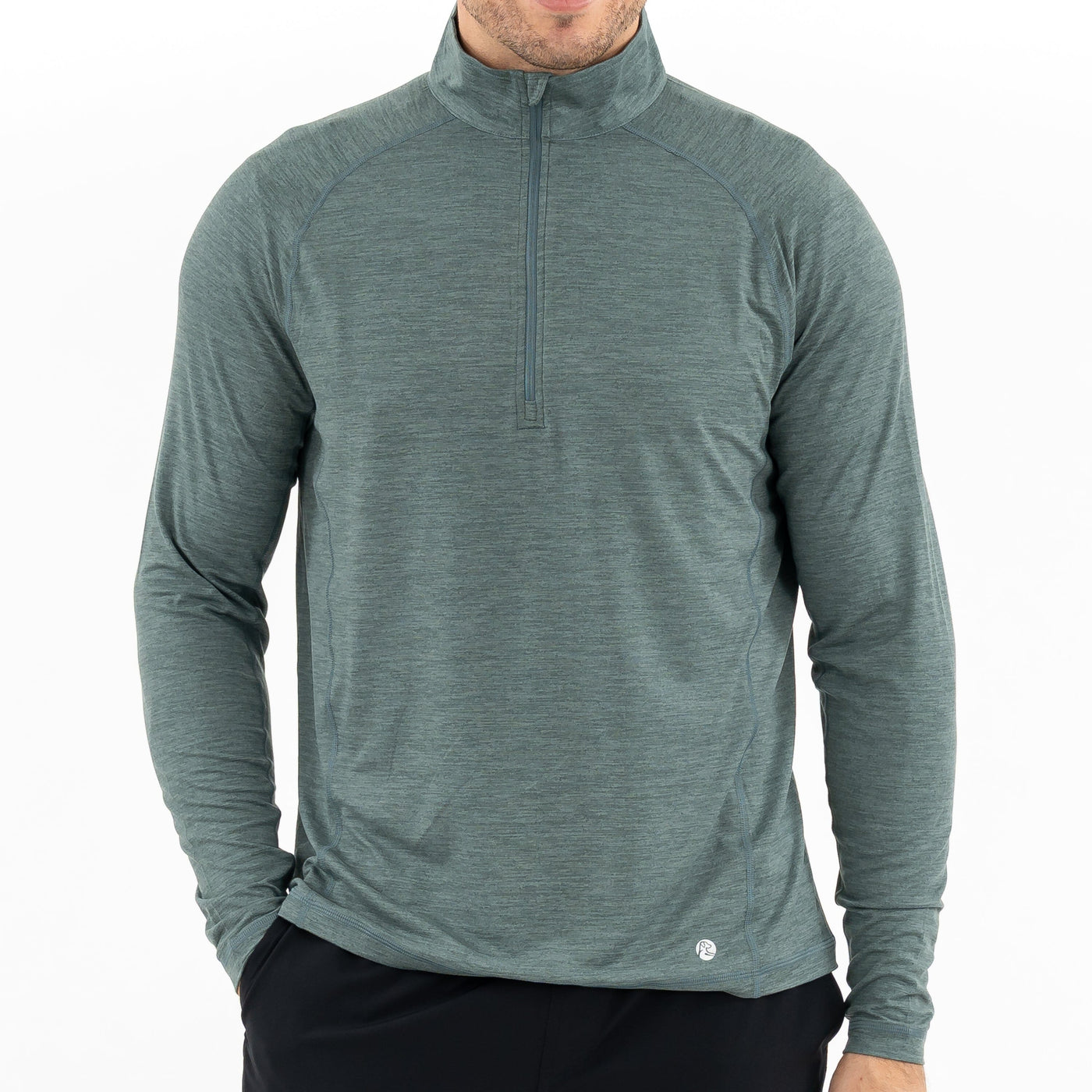 A man wears RHOBACK's Tailwind Performance Q-Zip in Heather - Jungle Green/Dusty Pine with black pants, standing against a plain white background. His face is partially out of frame.