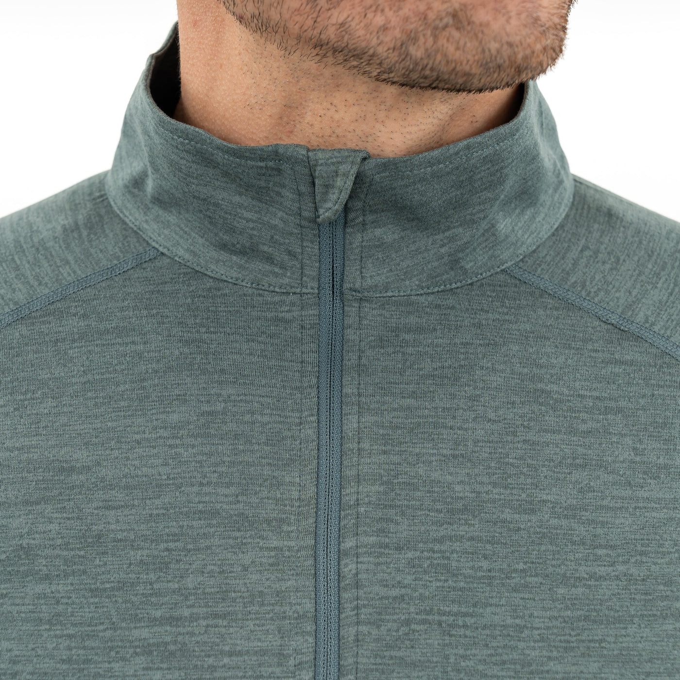 Close-up of a man's lower face and neck wearing the RHOBACK Tailwind Performance Q-Zip | Heather in Jungle Green/Dusty Pine, featuring moisture-wicking SkyKnit™ fabric and a high collar. Zipper is up, set against a plain white background.