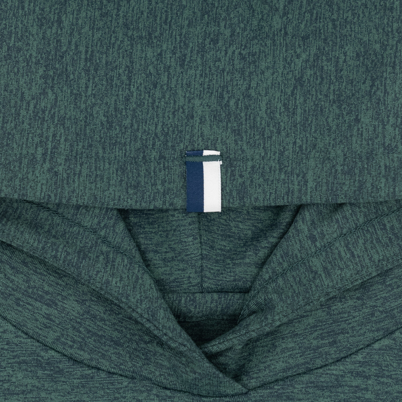 Close-up of the RHOBACK Lil' Hesi Performance Hoodie in Heather - Ponderosa Green/Willow Green, featuring VSoft™ fabric and a white and navy blue pull tab at the neckline, with the hood and folded upper section visible.