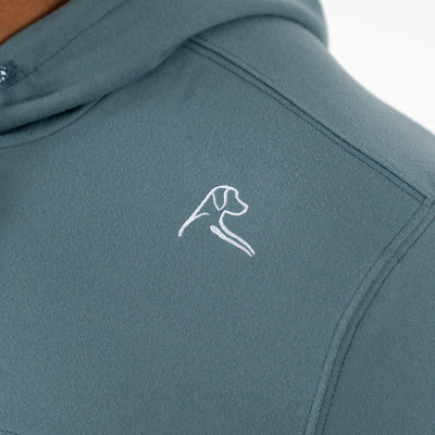 Close-up of the RHOBACK Hesi Performance Hoodie | Colorblock in Jungle Green/Aquafrost, made from VSoft™ fabric, with a small white minimalist dog's head and neck embroidered on the chest.