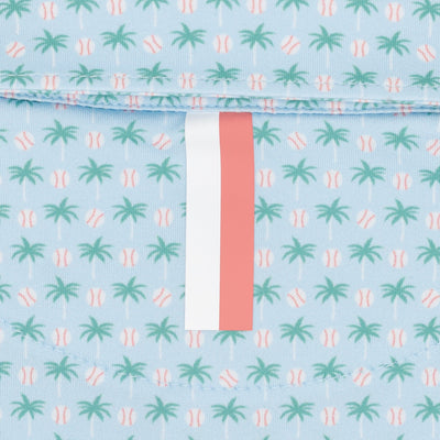 Close-up of The Lil' Spring Ball Performance Polo by RHOBACK in pale blue, featuring a sun-safe fabric patterned with green palm trees and pink baseballs—a perfect pick for toddler polo fans.