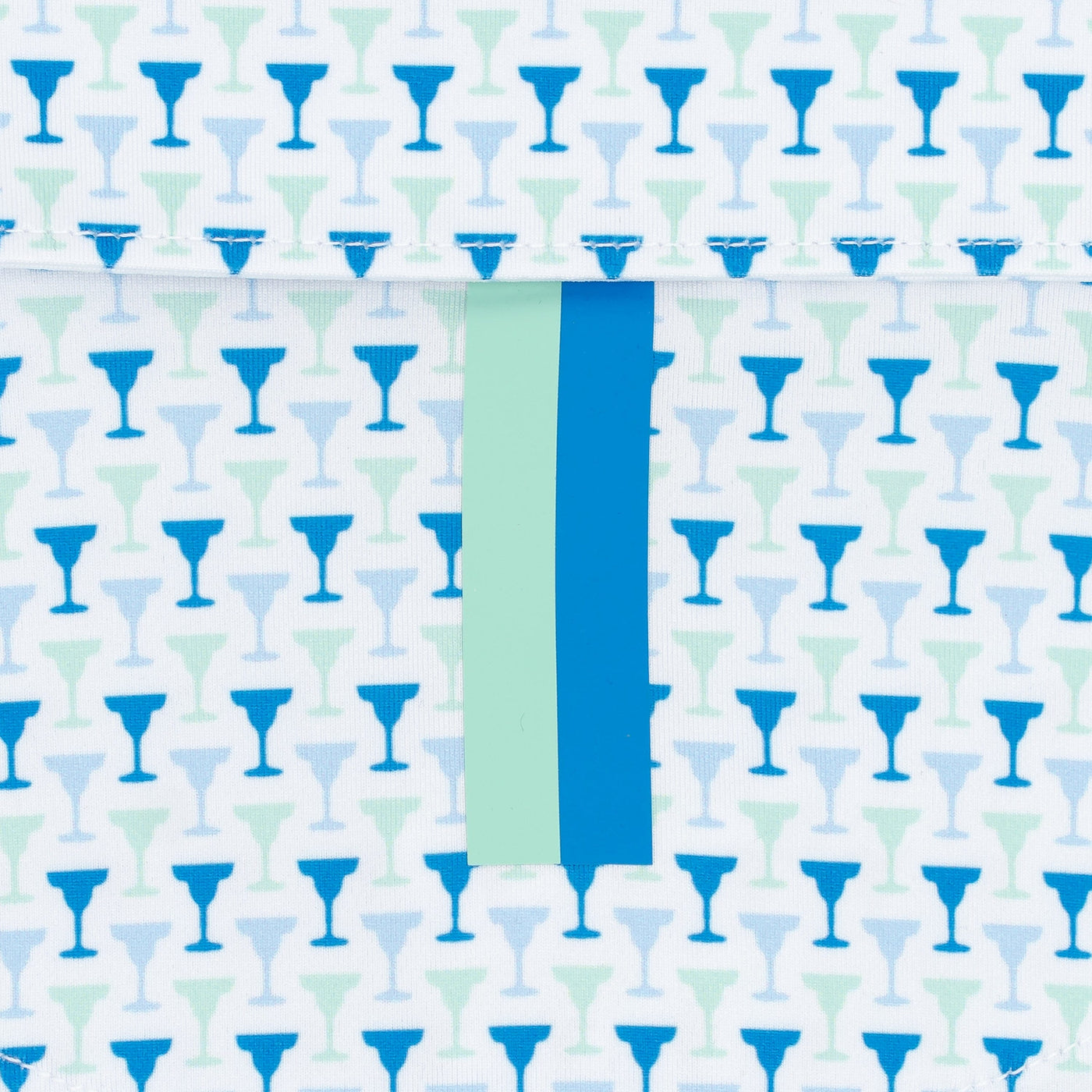 The Marg | Performance Polo by RHOBACK in White/Birdie Blue features repeating blue and teal cocktail glass silhouettes, a vertical mint-green and blue center stripe intersecting a top flap, and moisture-wicking fabric for comfort.