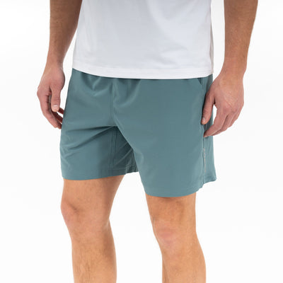 A person wearing a white t-shirt and RHOBACK's All-Active Short | Solid in Jungle Green, made from quick-drying, lightweight fabric, stands with arms relaxed at their sides against a plain white background (mid-torso to knees shown).