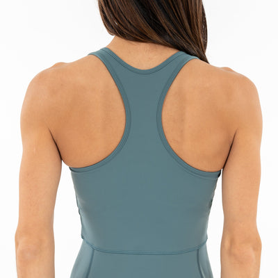 A woman is seen from the back wearing the RHOBACK Everyday Active Dress in Jungle Green. Her straight brown hair is partially visible against a plain white background.